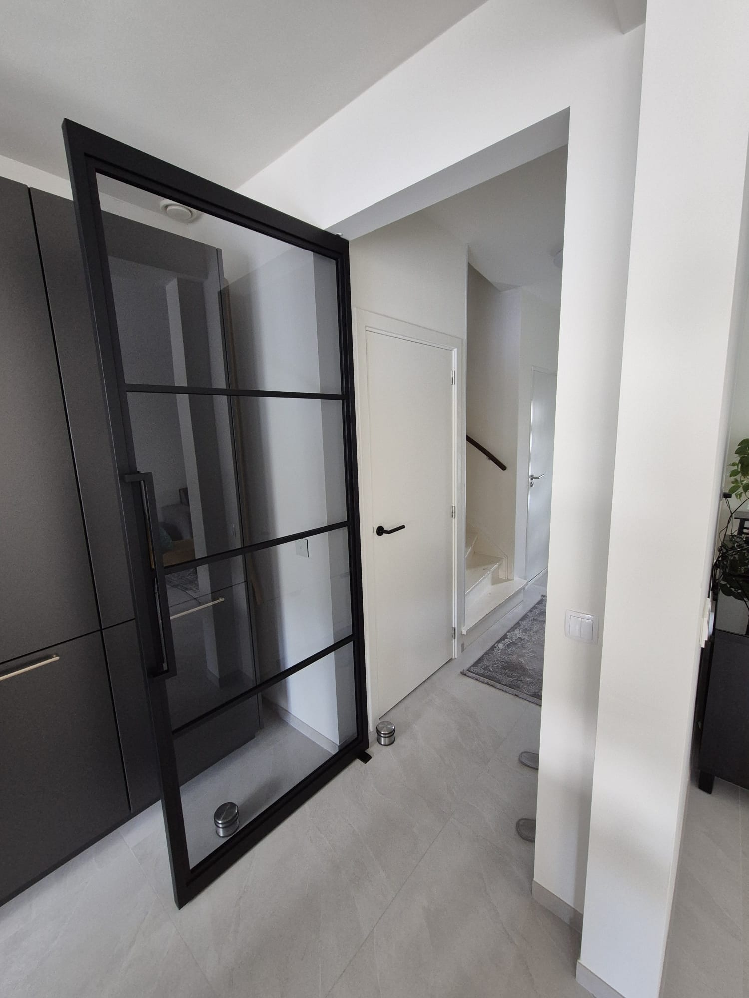 Hal met zwarte glazen deur en trap op de achtergrond